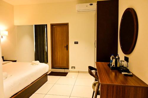 a hotel room with a bed and a wooden desk at Hotel S S International Coorg in Suntikoppa