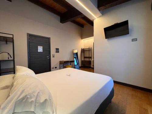 a bedroom with a white bed and a flat screen tv at Il Lavatoio Dimora Storica in Castel di Sangro