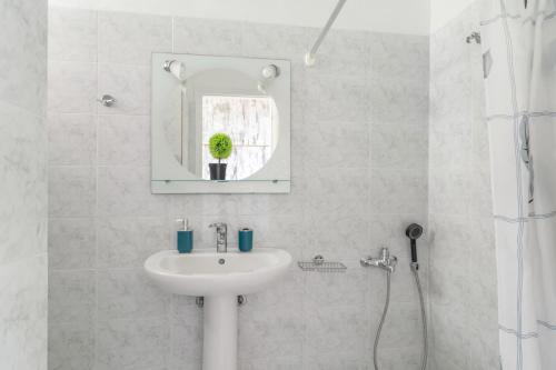 a white bathroom with a sink and a mirror at Christianna studios in Nikiana