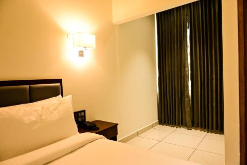 a hotel room with a bed and a window at Hotel S S International Coorg in Suntikoppa