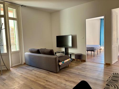 un salon avec un canapé et une télévision à écran plat dans l'établissement T3 rénové Centre historique de Perpignan, à Perpignan