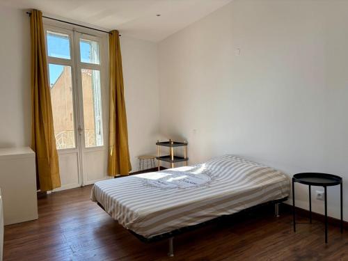 une chambre avec un lit et une grande fenêtre dans l'établissement T3 rénové Centre historique de Perpignan, à Perpignan