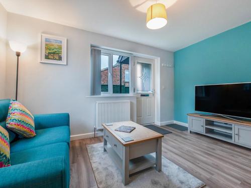 a living room with a blue couch and a flat screen tv at Ay Come Inn in York
