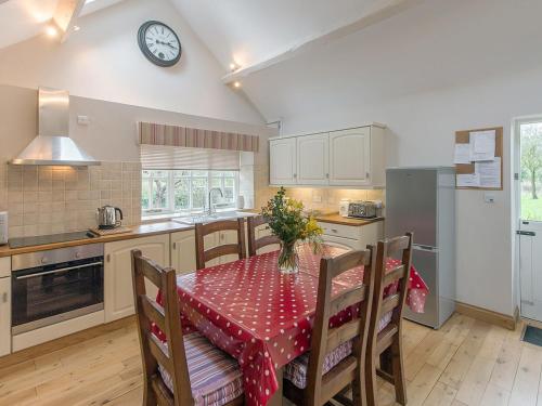 a kitchen with a table and a clock on the wall at Walkmill Lodge in Wentnor