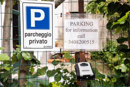 two signs on a fence with a parking sign and a cell phone at Romantic getaway on Lake Como in Brunate
