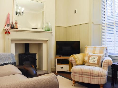 ein Wohnzimmer mit zwei Stühlen und einem Fernseher in der Unterkunft Darton Cottage in Whitby