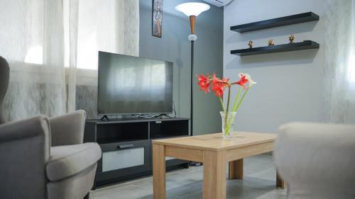 a living room with a television and a table with flowers at Urban Nest in Alexandroupoli