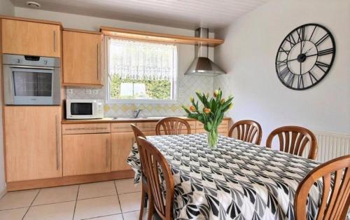 une cuisine avec une table et une horloge au mur dans l'établissement Gite de Kertanguy entre terre et mer, à Mespaul