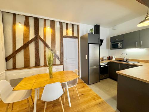 a kitchen with a wooden table and white chairs at Le Saint Melaine, Hyper centre de Rennes in Rennes
