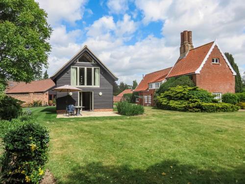 a house with a grass yard and a brick building at The Farmhouse - Uk45894 in Banham