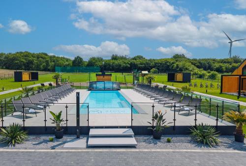 a swimming pool with lounge chairs and a windmill at Złota Palma Kopań -domki całoroczne nad morzem in Kopań