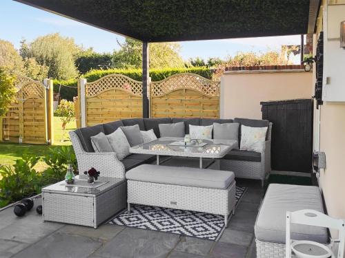 a patio with a couch and a table at Rose Cottage in Peldon