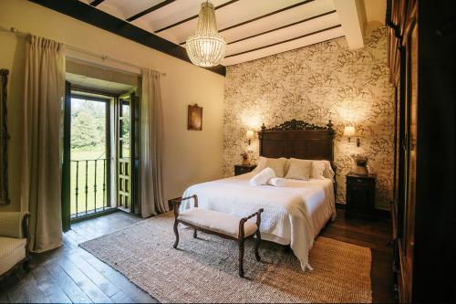 a bedroom with a bed and a chair and a window at Hotel Palacio de Caranceja in Reocín