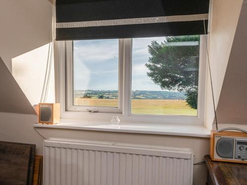 a window with a view of a field at Apartment Hole 18 34 in Nailsworth