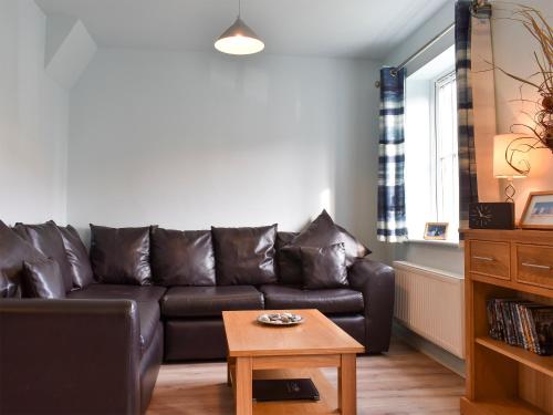 a living room with a leather couch and a table at Perran Cottage in Reighton