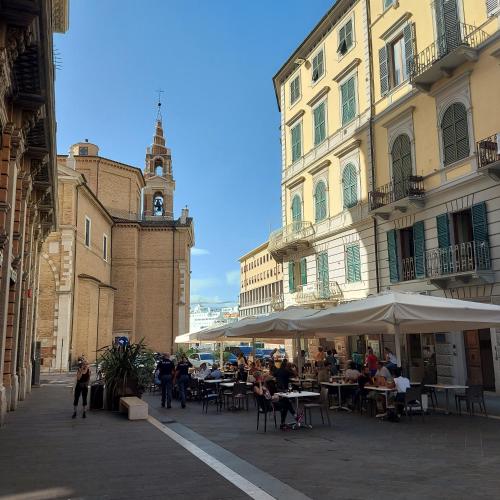 a group of people sitting at tables with umbrellas on a city street at Il Guasco Rooms in Ancona