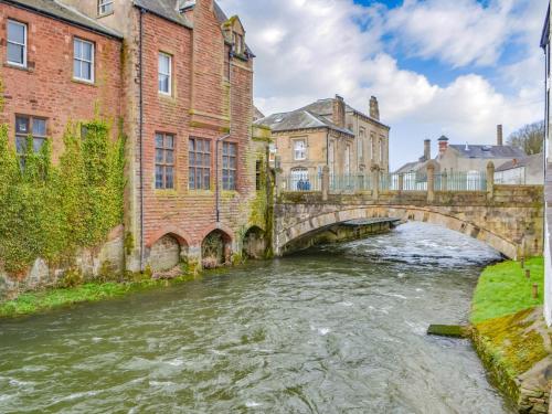 an old bridge over a river in a city at Hatters Croft in Cockermouth