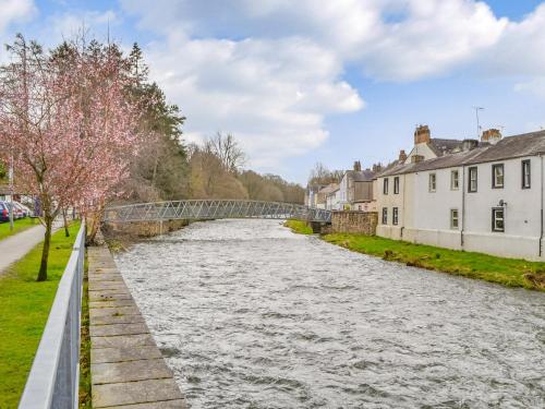a river in a town with a bridge at Hatters Croft in Cockermouth