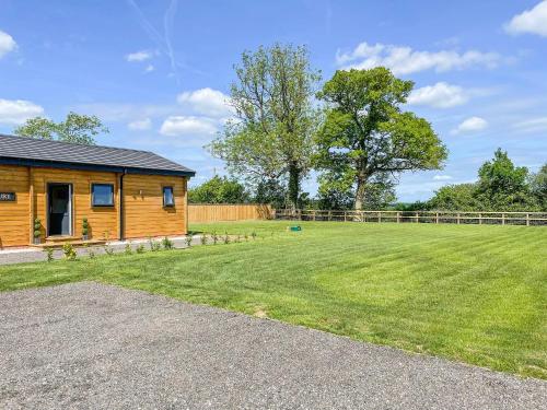 a log cabin with a large grass yard at Aylesbury Lodge in Halstead