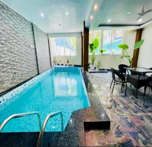 a swimming pool in a room with a table and chairs at The Shore Travelista in Rishīkesh