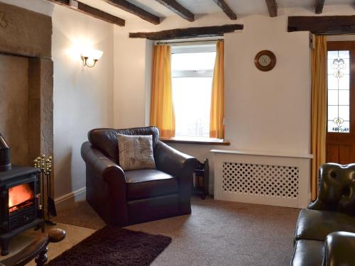 a living room with a leather chair and a fireplace at Wild Flower Cottage in Youlgreave