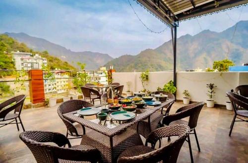 a table and chairs on a balcony with mountains in the background at The Shore Travelista in Rishīkesh