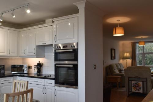 a kitchen with white cabinets and a stove top oven at Flat 18 Pochin House in St Austell
