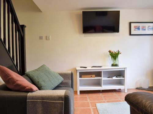 a living room with a couch and a tv on a wall at Barn Court Cottage in Washfield