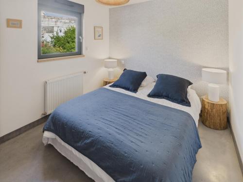 une chambre avec un lit avec des oreillers bleus et une fenêtre dans l'établissement Charmante maison pour 5 au coeur de Penmarch, à Penmarcʼh