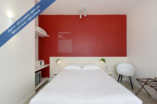 a bedroom with a white bed and a red wall at Hôtel Les Voiles in Toulon