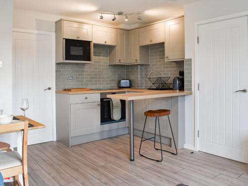 a kitchen with white cabinets and a table and stool at Hillside At Bowness in Windermere