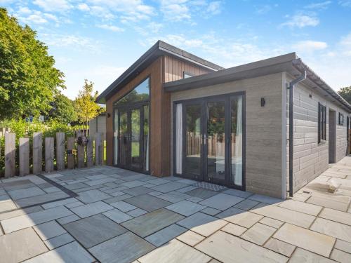 a small house with glass doors on a patio at Three Sandbanks in Benllech