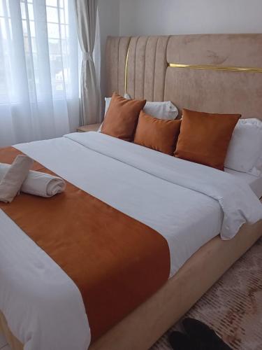 a large bed with brown and white sheets and pillows at Belaire Bnb one bedroom in Thindigua kiambu road in Kiambu