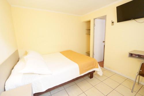 a small bedroom with a bed and a television at Hotel Frontera in Antofagasta