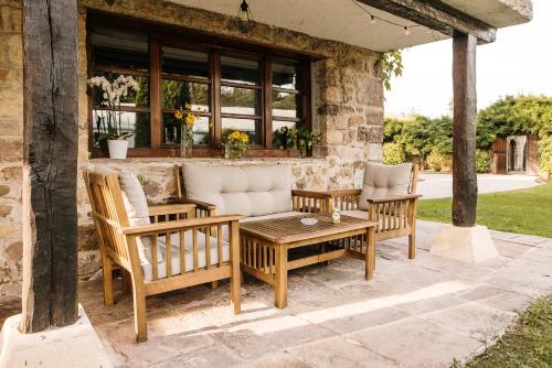 a patio with a couch and two chairs and a table at Hotel Palacio de Caranceja in Reocín