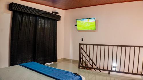 Un dormitorio con una cama y un televisor en la pared. en Toucan Villa Rio Cuarto, en Río Cuarto