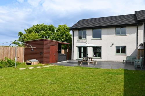 a house with a patio with a picnic table at Aurora - Self Catering, Kirkwall, Quiet Location with Luxury Hot Tub in Orkney