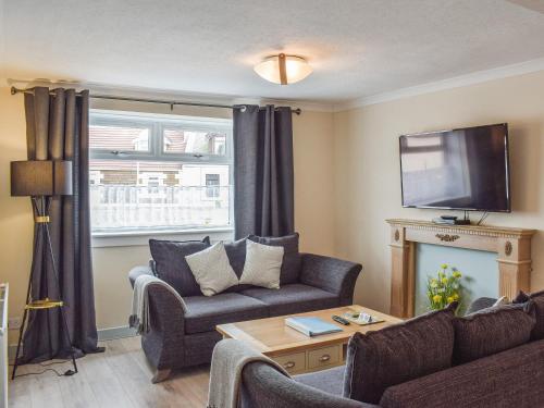 un soggiorno con un divano e una TV di Corner Cottage a Girvan