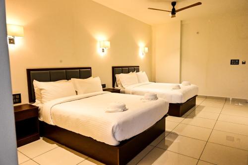 a hotel room with two beds with white sheets at Hotel S S International Coorg in Suntikoppa