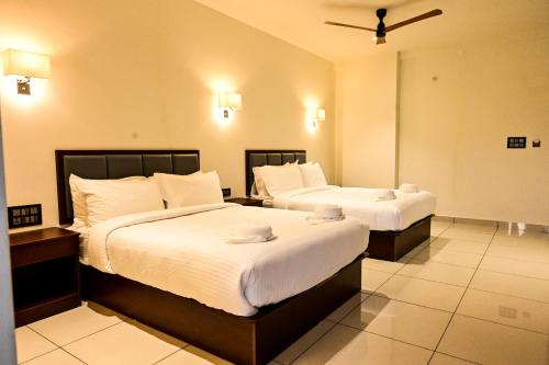 a hotel room with two beds with white sheets at Hotel S S International Coorg in Suntikoppa