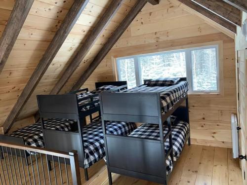 a room with four bunk beds in a cabin at Chalet bois rond, Spa, rivière & nature in Lac-aux-Sables