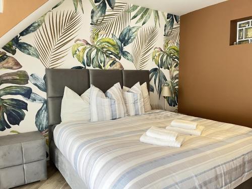 een slaapkamer met een groot bed met tropisch behang bij La Petite Saulaie - Proche circuit 24h - 6 pers in Changé