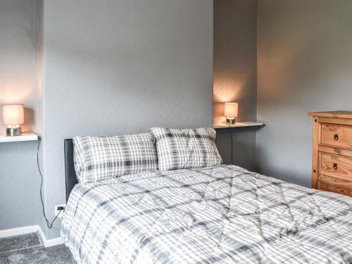 a bedroom with a bed with a plaid blanket and two lamps at White Rose Apartment in Bridlington