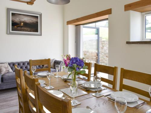 a dining room with a table with a vase of flowers at Deer Park - Uk33360 in Reeth