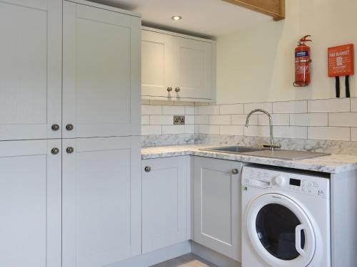 a white kitchen with a washing machine and a sink at Deer Park - Uk33360 in Reeth