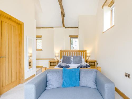 a bedroom with a bed and a blue couch at Olive Barn in Witheridge