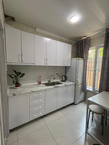 kuchnia z białymi szafkami, zlewem i lodówką w obiekcie Sayakatchy hostel w mieście Biszkek