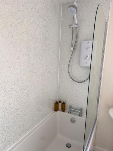 a bathroom with a shower and a white bath tub at Williamsfield Cottage in Holywood