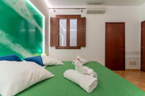 a room with a green bed with towels on it at "L'Oasi di Favignana" Room and Charme in Favignana