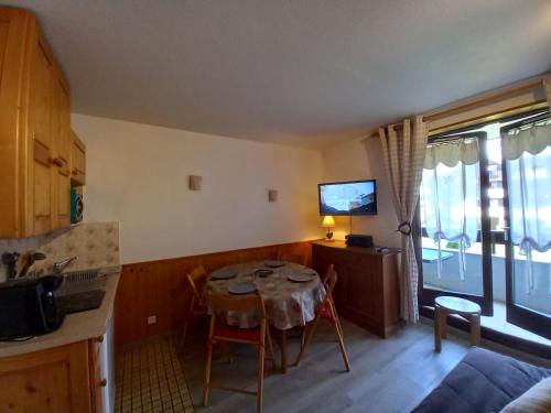 une cuisine avec une table et des chaises ainsi qu'une télévision dans l'établissement Bel appartement Samoens La Cour classe 2 etoiles, à Samoëns